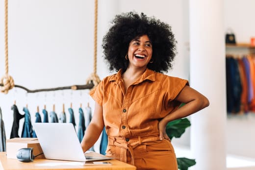 Gut gelaunte Boutique-Inhaberin, erfreut über Produkttexte in ihrem Online-Shop: Modetext, verkaufsstark und informativ