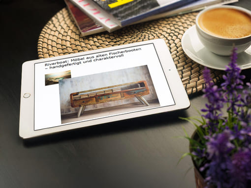 Hand auf Sofalehne hält Smartphone mit Produktbeschreibung: ein Referenz-Text vom Produkttexter, Modetexter, Möbeltexter.